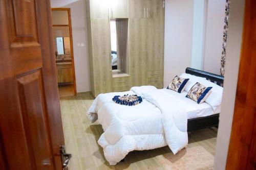 1 dormitorio con 1 cama con sábanas blancas y espejo en Lukemanbnb Own Compound, en Voi