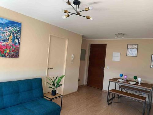 uma sala de estar com um sofá azul e uma mesa em Departamento 3 piezas Centro Chillan - Parking - Vista - Factura em Chillán
