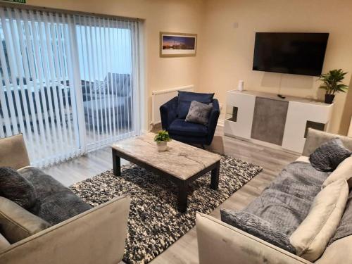 a living room with couches and a table and a tv at Luxury 5-bed House near NEC & BHX in Solihull