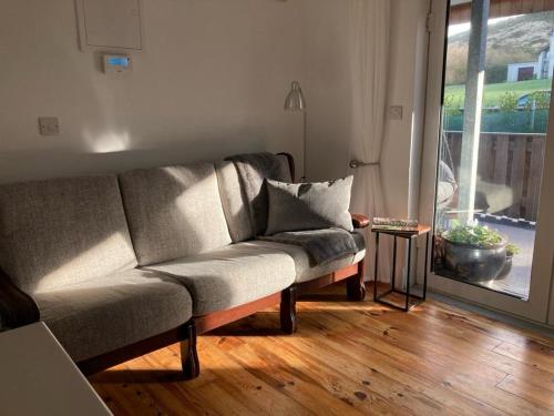 a couch sitting in a living room next to a window at Cille Apartments, Ballyferriter village in Ballyferriter