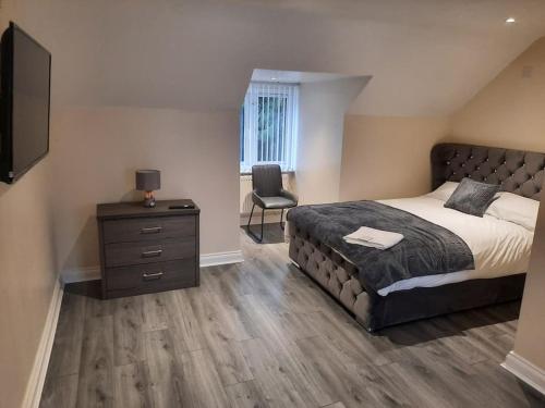 a bedroom with a bed and a dresser and a chair at Stunning 5-bed ensuite House Solihull in Solihull