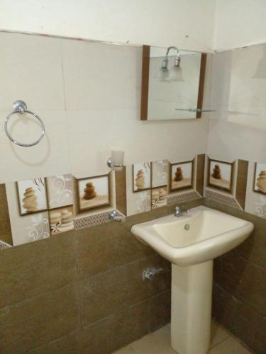 uma casa de banho com lavatório e algumas fotografias na parede em Green View In Nuwaraeliya em Nuwara Eliya