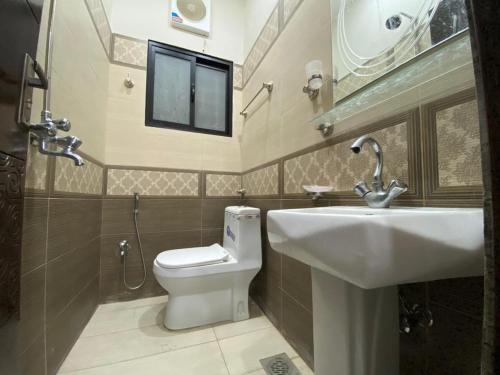 uma casa de banho com um lavatório, um WC e um espelho. em Uptown Residences em Gujrānwāla