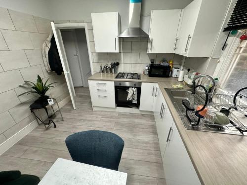 a kitchen with white cabinets and a sink and a stove at Whitechapel Station Rooms R1 in London