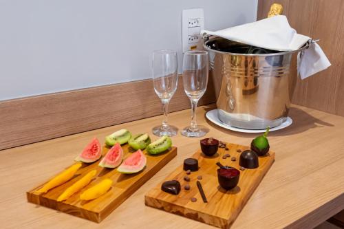 a table with two cutting boards with fruit and wine glasses at ibis Styles Goiânia Shopping Estação in Goiânia