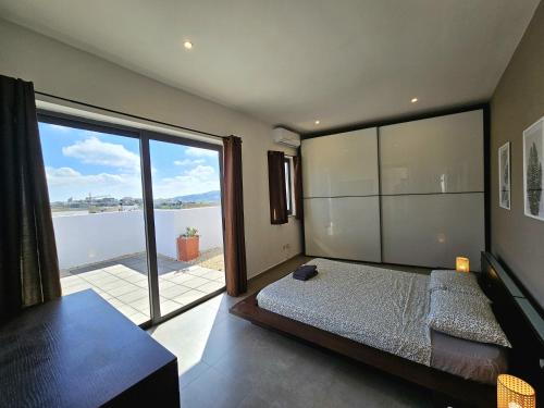 um quarto com uma cama e uma grande janela em Malta Unique Penthouse Spacious Terrace-Sleeps 8 em Mġarr