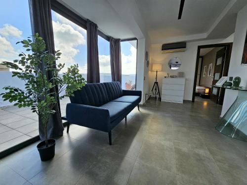a living room with a blue chair and large windows at Malta Unique Penthouse Spacious Terrace-Sleeps 8 in Mġarr