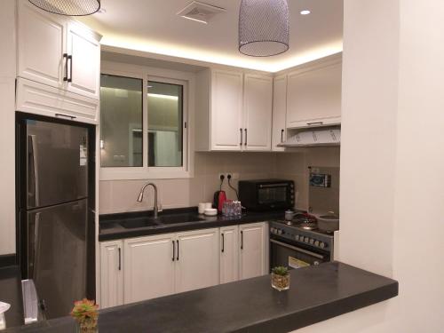 a kitchen with white cabinets and a stainless steel refrigerator at فيلا الجبل in Al Hada