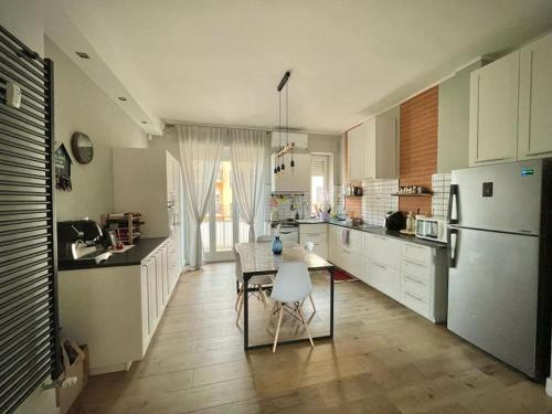 a kitchen with a table and a white refrigerator at Appartamento Ca' Fola Alba in Alba