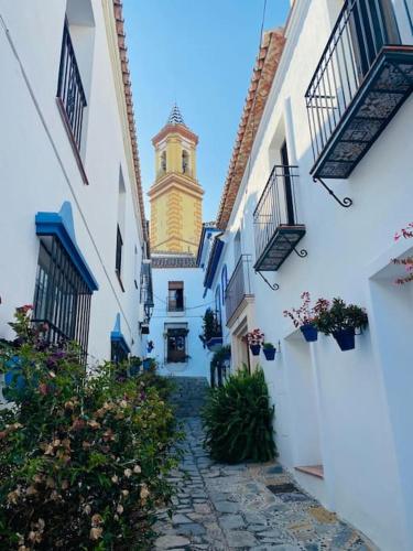 a narrow alley with a clock tower in the distance at Casa Desire in Estepona