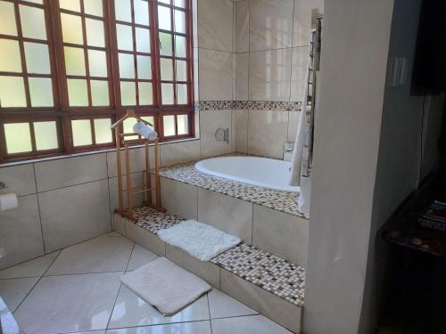 a bathroom with a bath tub and a window at Garrett Guest House in Pretoria