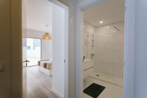 a bathroom with a walk in shower next to a bed at Best Houses 104 - Supertubos Beach Apartment in Atouguia da Baleia