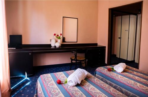 two beds in a room with a desk and a mirror at Hotel Milano Pool & Garden in Salice Terme