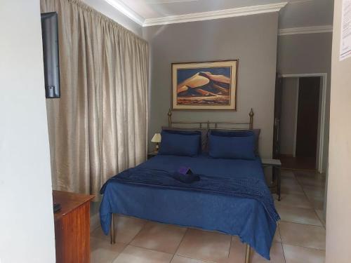 a bedroom with a blue bed with blue pillows at Garrett Guest House in Pretoria