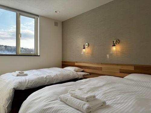 two beds in a room with a window at Mountain Villa ニセコ in Kutchan