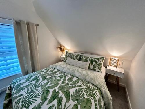 a bedroom with a bed with a green and white comforter at The Coach House - Bournemouth in Bournemouth