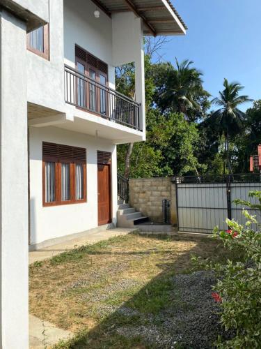 a house with a balcony and a yard at Peacock Residence in Dickwella