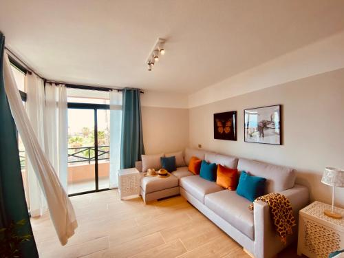 een woonkamer met een bank en een groot raam bij LA PAZ. Lovely apartment overlooking the golf and sea in San Miguel de Abona