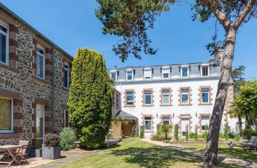 ein großes weißes Gebäude mit einem Baum davor in der Unterkunft Hôtel Les Costans, The Originals Relais in Perros-Guirec