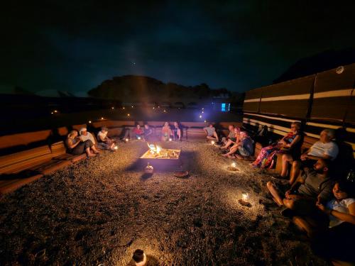 a group of people sitting around a fire pit at night at Wadi Rum Candles Camp in Wadi Rum