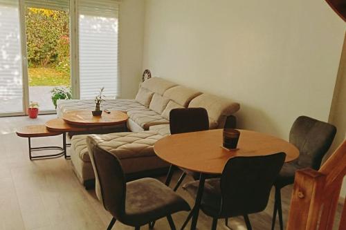 un salon avec un canapé et deux tables et chaises dans l'établissement Les Villas Terrasses (close Stade de France) idéal JO, à Saint-Denis