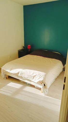 un lit dans une chambre avec un mur bleu dans l'établissement Les Villas Terrasses (close Stade de France) idéal JO, à Saint-Denis