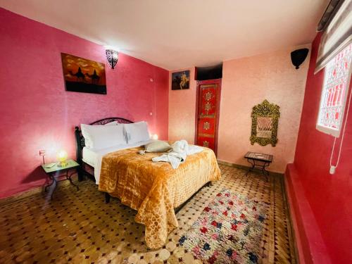 um quarto com uma cama e uma parede vermelha em Riad Layla Rouge em Marrakech