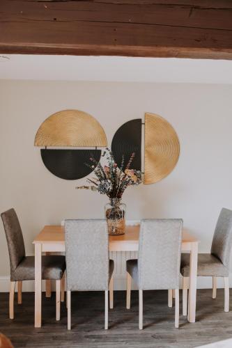 a dining room table with chairs and a vase of flowers at Pattys Barn Holiday Cottages, Cabins and Venue Hire in Cockerham