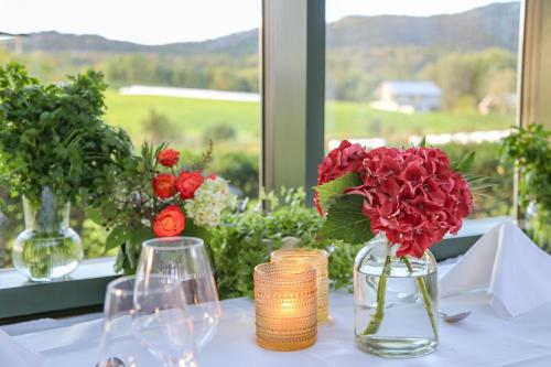 a table with red flowers in a glass vase at Kronen Gaard Hotel in Sandnes