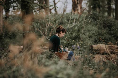 a woman sitting in a field with a basket at Pattys Barn Holiday Cottages, Cabins and Venue Hire in Cockerham