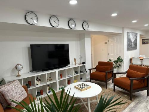 a living room with a tv and clocks on the wall at Garden's Grace: Whispers in Silver Spring