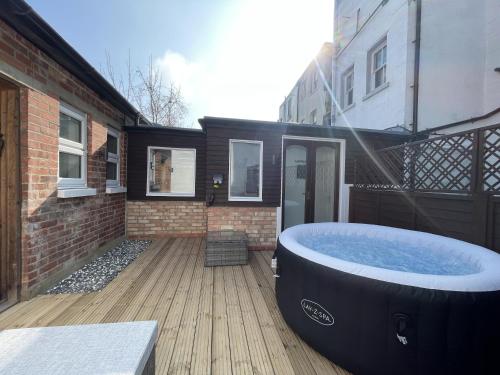 a large bath tub sitting on a deck next to a building at Coastal Comfort, Hot Tub Lodge in Margate