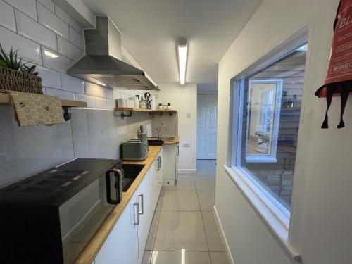 a kitchen with white cabinets and a window in it at Coastal Comfort Seaside Cabin with Spacious Garden in Margate