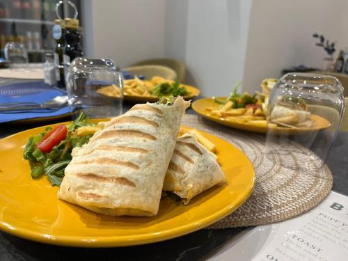 a yellow plate with a sandwich and salad on a table at The Central guesthouse in Tal-Pietà