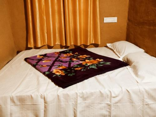 a blanket sitting on top of a bed at Cosmic Mud House Kanthalloor in Kanthalloor