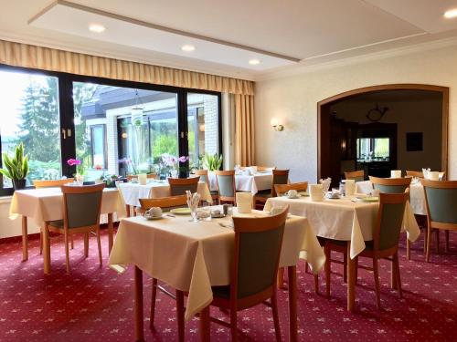 a dining room with white tables and chairs at Landhotel Hubertus in Unterelsbach
