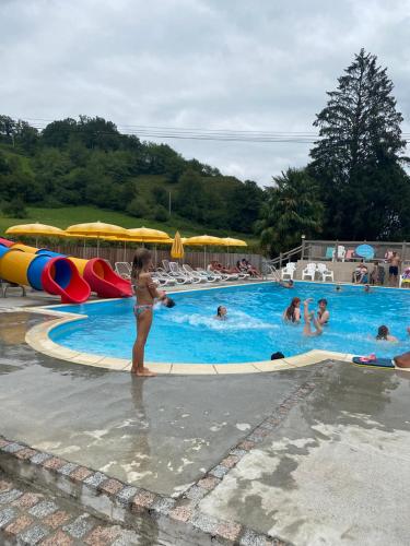 une petite fille debout en face d'une piscine dans l'établissement Mobil Home XXL 4 chambres - Camping À l'Ombre des Tilleuls, à Peyrouse