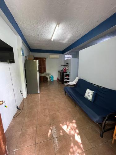 a room with a blue bed and a kitchen at Celi’s Ocean Apartment in Caye Caulker