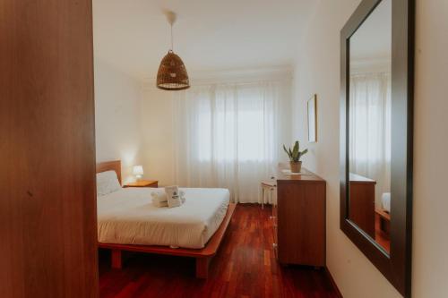 een slaapkamer met een wit bed en een spiegel bij Best Houses 68 - Downtown Ferrel in Ferrel