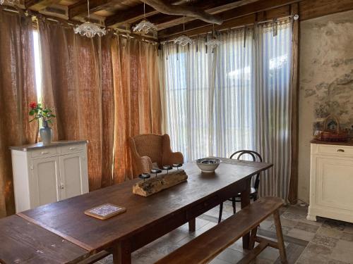 a dining room with a wooden table and curtains at Chambre d'Hôtes chez Gustave & Compagnie in Choussy