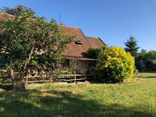 a house with a tree and a fence in a field at Chambre d'Hôtes chez Gustave & Compagnie in Choussy