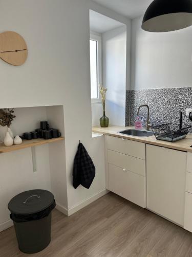 a white kitchen with a sink and a trash can at La terrasse : Appartement chic 2 chambres au coeur de Pau in Pau