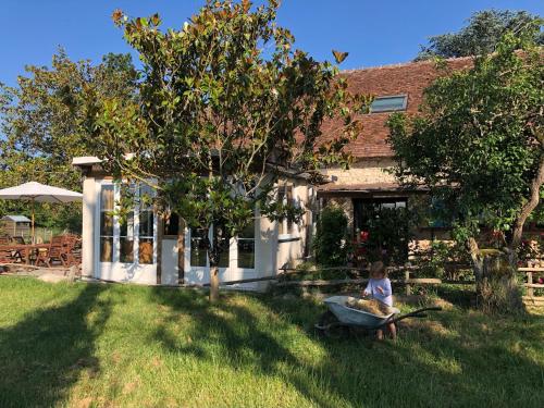 a little girl sitting in a wheelbarrow in front of a house at Chambre d'Hôtes chez Gustave & Compagnie in Choussy