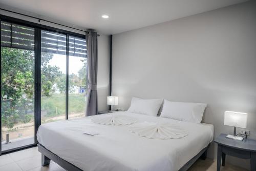 a white bed in a bedroom with a large window at The Villager Fishermans Village in Bophut