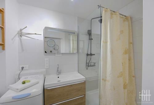 une salle de bain blanche avec un lavabo et une douche dans l'établissement L'Acacia Centre Ville, à Tours