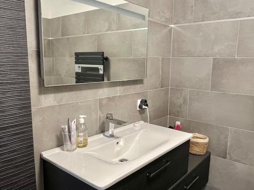 bagno con lavandino bianco e specchio di Appartement T3 Lucciana a Lucciana