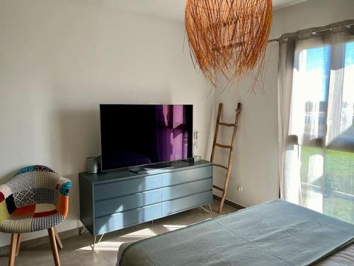 - un salon avec une télévision sur une commode et une chaise dans l'établissement Appartement T3 Lucciana, à Lucciana