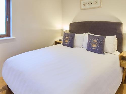 una camera da letto con un grande letto bianco con cuscini di Host & Stay - Cobnut Barn ad Ashford