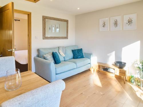 a living room with a blue couch and a table at Host & Stay - Cobnut Barn in Ashford