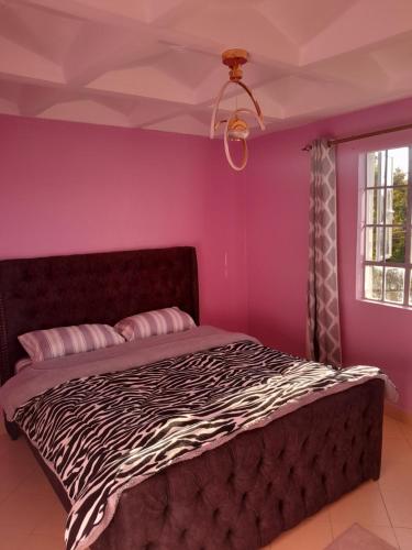 a bedroom with a zebra print bed with purple walls at Sweet Homes S.Bypass in Kikuyu